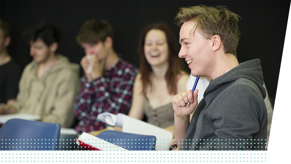 A LAMDA learner laughs holding a script