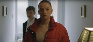 Two young women stand inside the entrance hall of a residence
